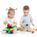 little children playing together with construction set over white background
